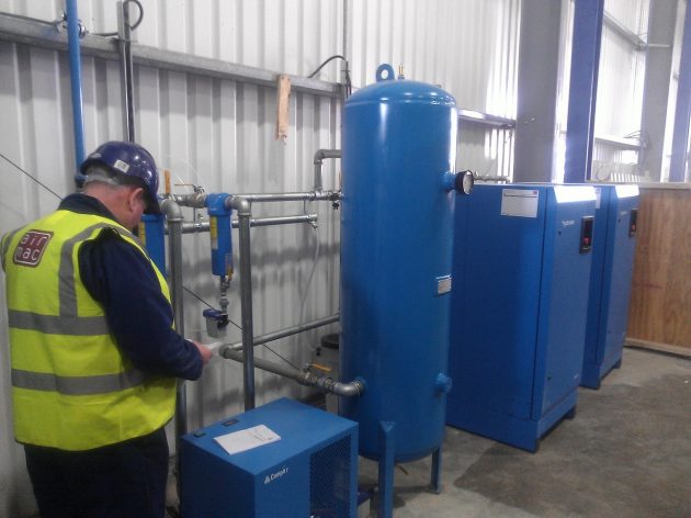 air mac employee providing maintenance to 3 compair air compressors and pipework