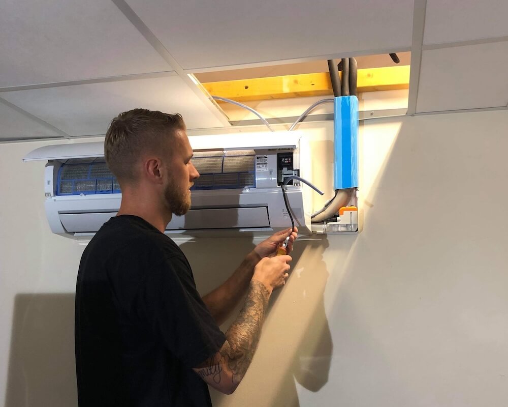 Airmac employee providing air conditioning maintenance for a customer